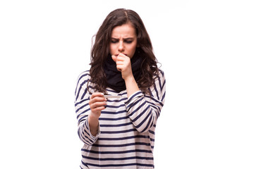 Young sick woman coughs in scarf and home clothes looking at thermometer. Sick girl with a thermometer on a white background, isolate, flu, colds