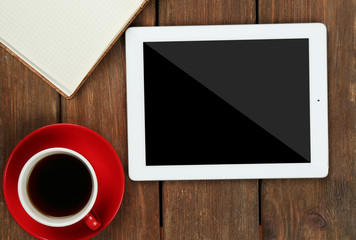 Digital tablet with cup of coffee and notebook on wooden table, closeup