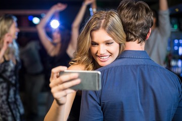 Woman using smartphone while hugging boyfriend