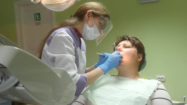 4k Young female patient receiving dental care from a dentist