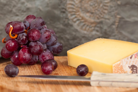 Käse und rote Trauben auf Holzplatte