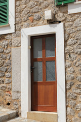 Fototapeta na wymiar brown wooden door in stone wall, mediterranean style
