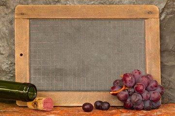 Tafel, Trauben, Weinflasche vor Steinmauer