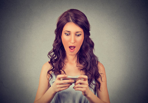anxious shocked girl looking at phone seeing bad news with stunned emotion on her face