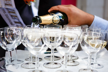The waiter pours champagne into crystal glasses