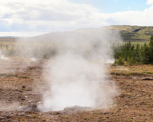 Fototapeta na wymiar Geysir Geothermal Field. Steam rises from a sulphur pool at the Geysir Geothermal Field and located in Haukadalur in Iceland. The tourist attraction is part of the Golden Circle tourist trail.