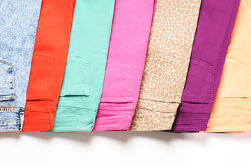 A number of colored jeans on a white background