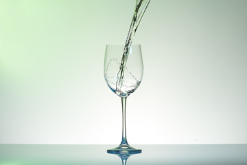 Water pouring into a wineglass creating swirl and splashes.