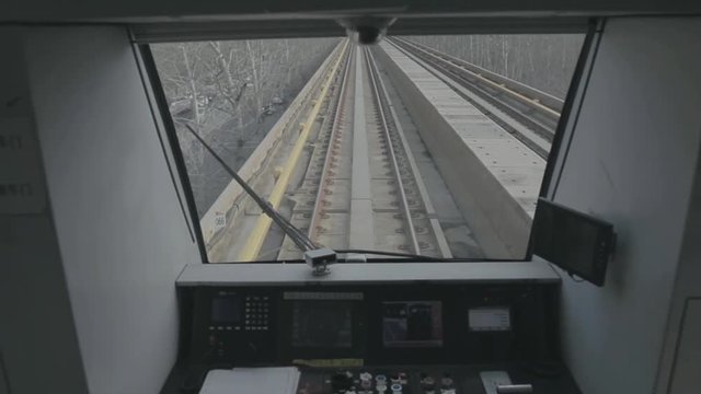 View of subway train operator cabin.  Express train moving fast. View over railroad track.Handheld wide shot