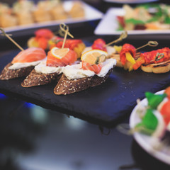 Beautifully decorated catering banquet table with different food snacks and appetizers with sandwich, caviar, fresh fruits on corporate christmas birthday party event or wedding celebration