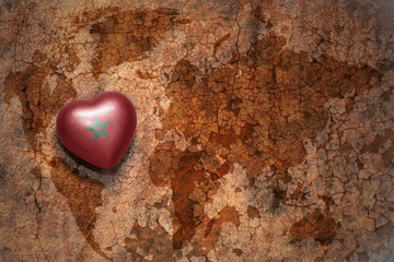 heart with national flag of morocco on a vintage world map crack paper background.