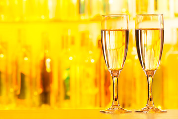 Two full flute glasses standing on bar counter