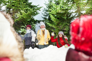 Kids playing snowballs hiding behind snow tower