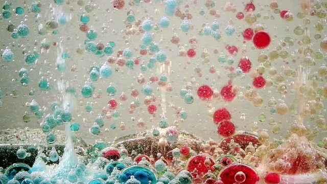 Bright and colorful multi-colored liquid in motion. Lava lamp with green, yellow, blue, purple flowers. Movement of ink of different colors in the oil. HD