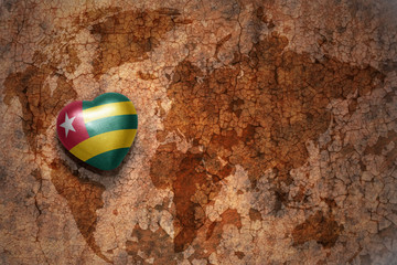 heart with national flag of togo on a vintage world map crack paper background.