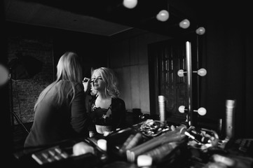 Fototapeta na wymiar Backstage scene: Professional Make-up artist doing glamour model makeup at work