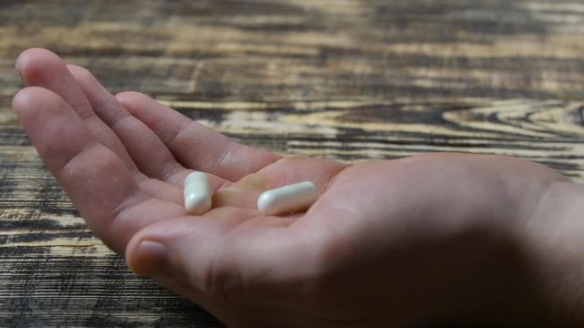 Close up of man pouring pills into her hand. Medical Capsules On A Palm Of A Hand