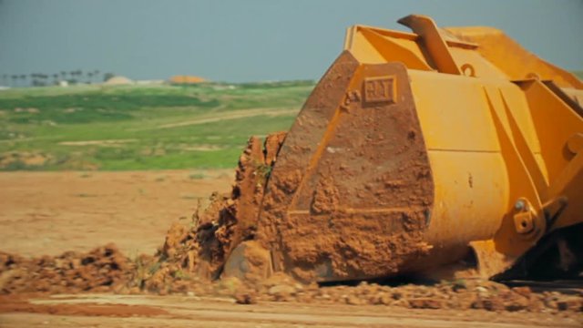 Tractor with a bulldozer moving soil at a construction site.