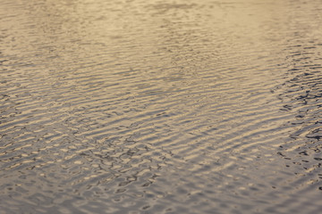 Ripples on the water at yellow sunrise background
