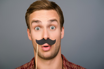 Close up portrait of surprised funny man holding paper mustache