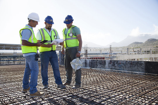 Construction workers talking on rebar at construction site