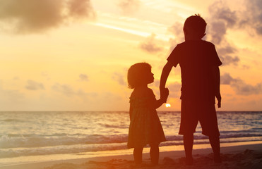 little boy and girl holding hands at sunset