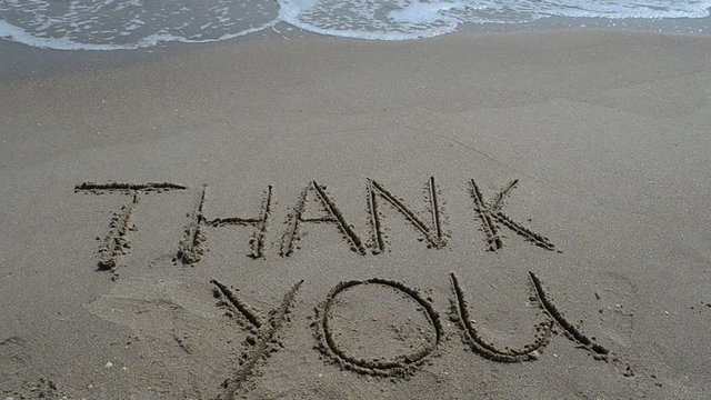 Thank you handwritten in sand on a beach