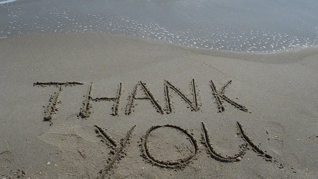Thank you handwritten in sand on a beach
