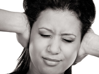 Mixed race woman closing ears with hands.