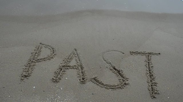 The inscription "PAST" on a wet sand seacoast.