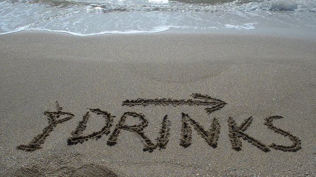 Inscription Drinks and the arrow drawn on the beach sand with a soft transparent