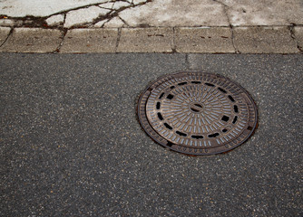 Abstract manhole cover on asphalt 