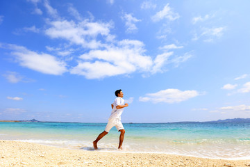 南国の美しいビーチを走る笑顔の男性