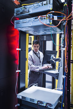 Technician working on desktop computer in server room