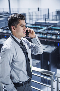 Businessman talking on a mobile phone with server room in background