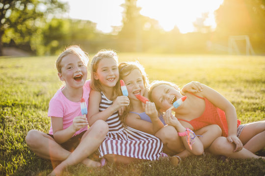 Girls eating popsicles in sunny field