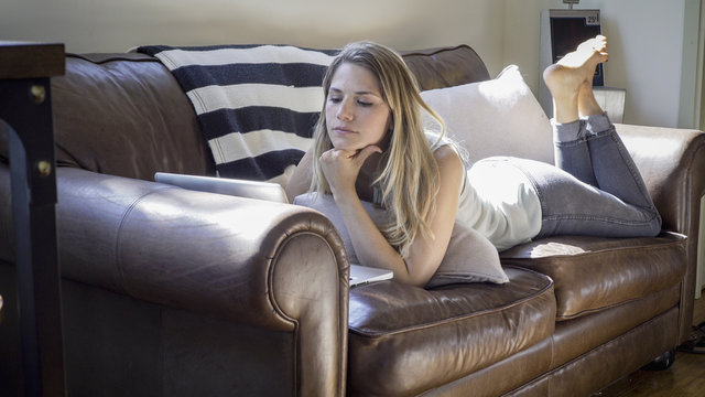 Caucasian woman using laptop on sofa