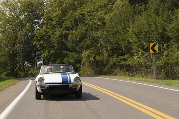 Couple driving convertible on rural road