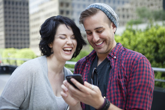 Caucasian Couple Using Cell Phone In City