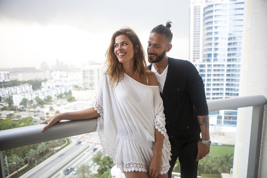 Hispanic couple standing on urban balcony