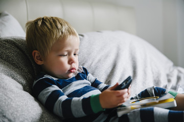 Baby boy playing with cell phone on bed