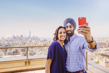 Indian couple taking selfie over New York cityscape, New York, United States