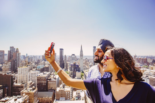 Indian couple taking selfie over New York cityscape, New York, United States