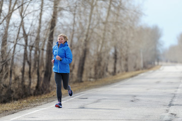 Runner woman running on road in beautiful nature. Jogging traini
