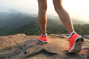 young healthy woman legs on mountain peak rock