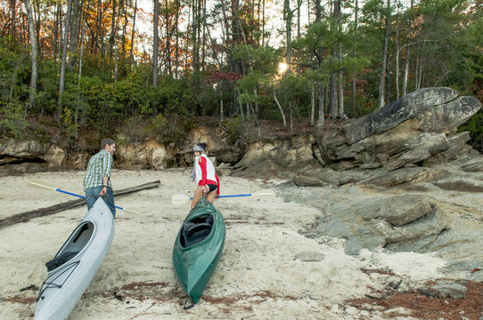 Couple pulling kayaks on rocks