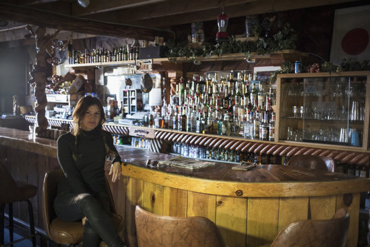 Woman sitting at counter in empty bar