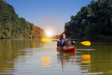 The man is kayaking on the river.