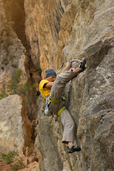 Young male climber hanging on a cliff with a rope.