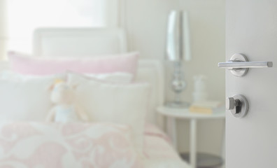 opened white door to cozy bedroom with pink and white pillows on bed